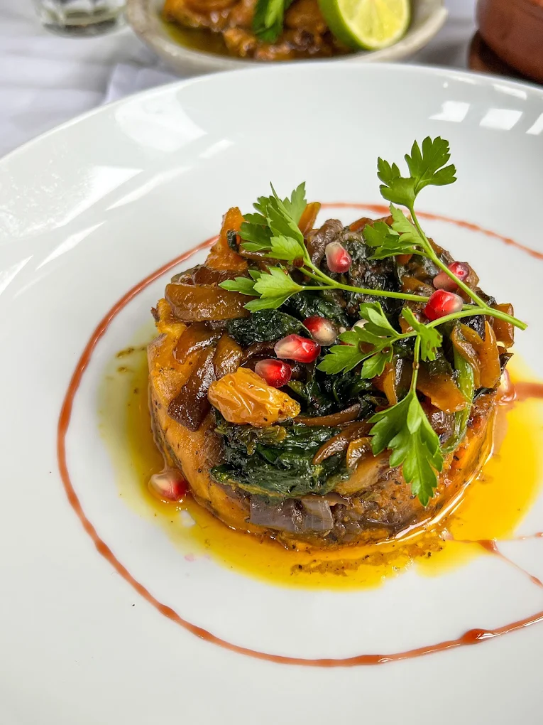 Plated dish with caramelised onions, spinach and pomegranate